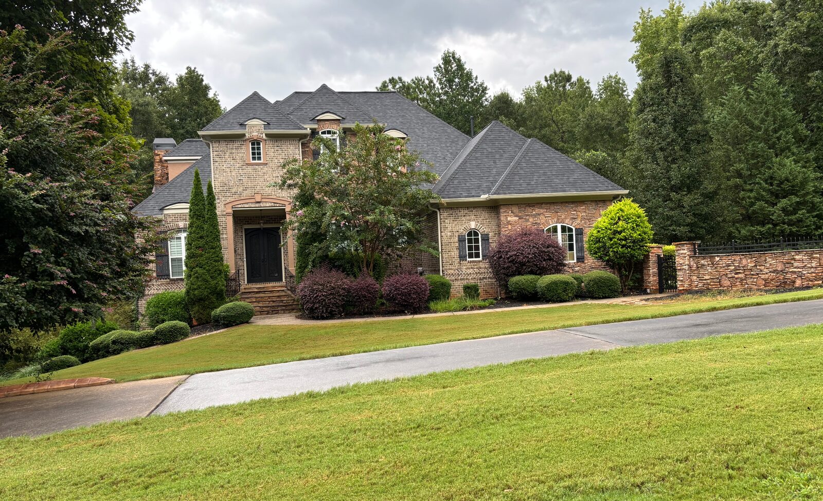 Brick custom home with stone accents and mature landscaping.